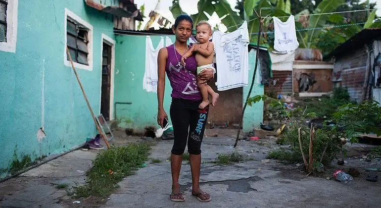 Mujer con su hija frente a su vivienda en un barrio popular de Honduras.